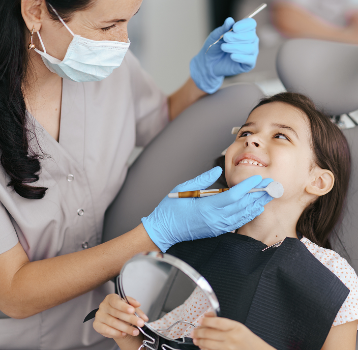 Smiling girl about to have her teeth cleaned by a dental hygeinist.